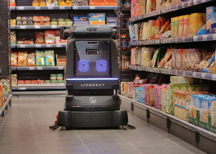 Autonome Reinigung mit Roboter von Salesmotion Robotics bewegt sich im Gang eines Lebensmittelgeschäfts zwischen den Regalen mit verpackten Lebensmitteln.